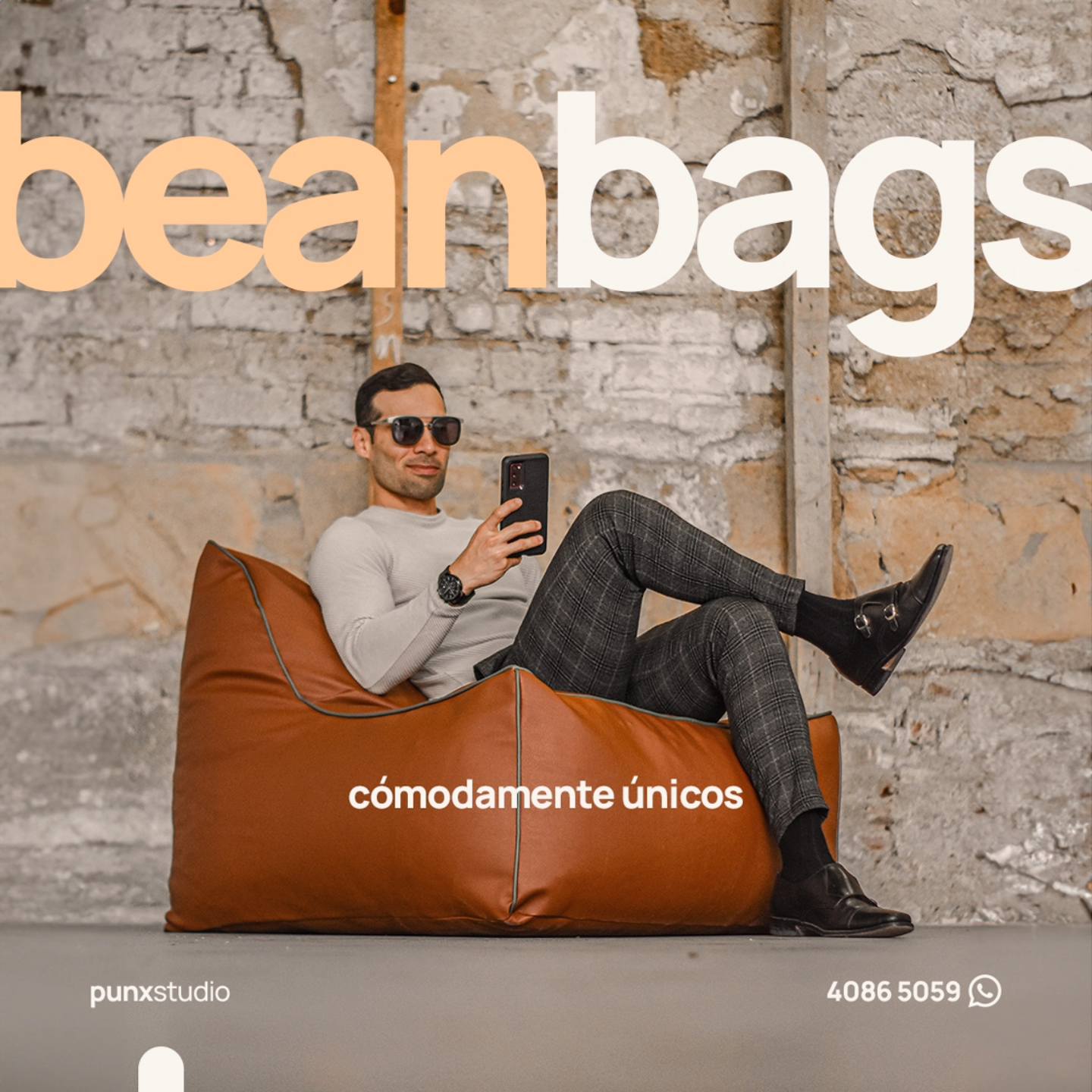 Hombre sentado en un bean bags con un teléfono móvil.